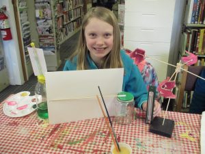 Weather Club member showing off all the weather instruments she made (barometer, anemometer, and thermometers).