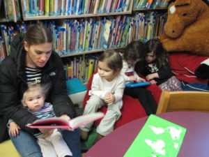 Woman reading books to small children