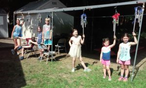 Kids standing below their metal windchimes.