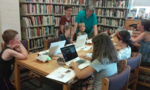 Kids at a table working on computers.